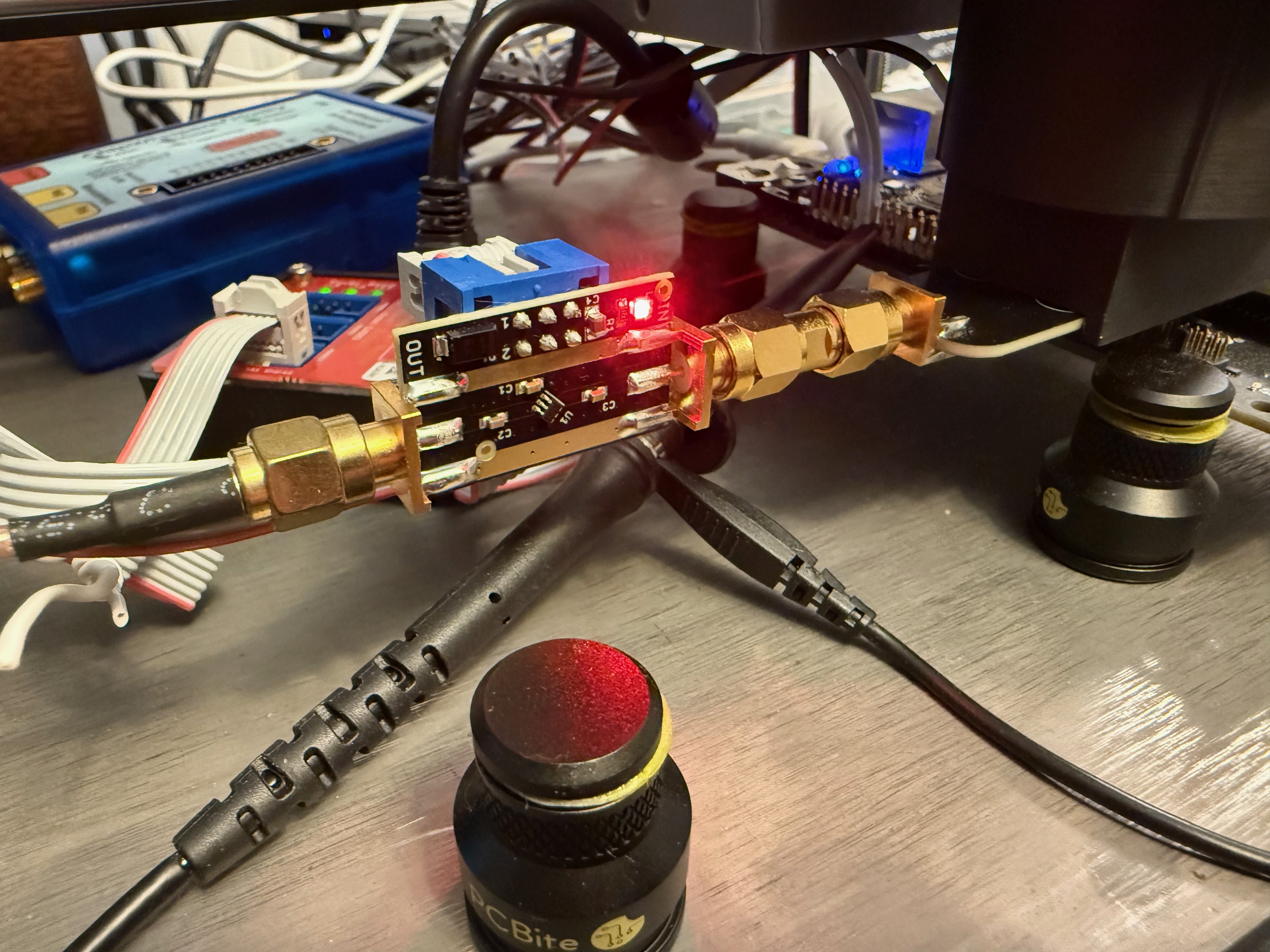 NewAE amplifier connected beside the probe holder, with the ChipWhisperer Husky in the background.